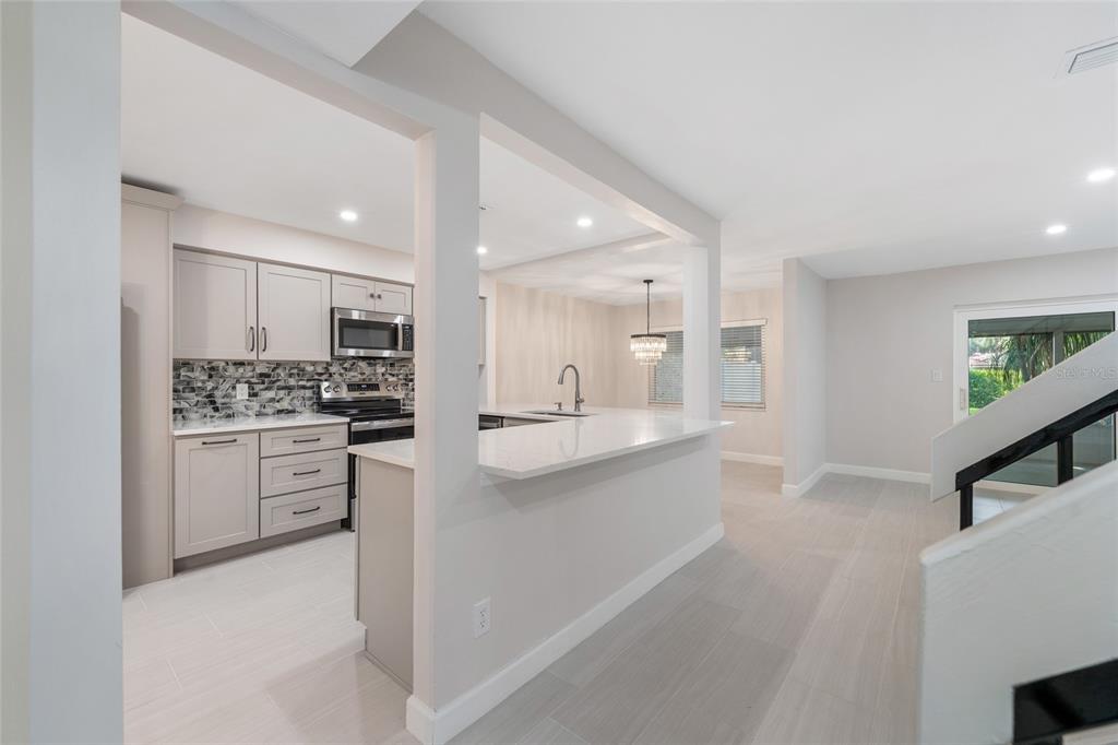 A modern kitchen features light gray cabinets, a quartz breakfast bar, and light tile flooring — 8137 CITRUS CHASE DRIVE, ORLANDO, FL