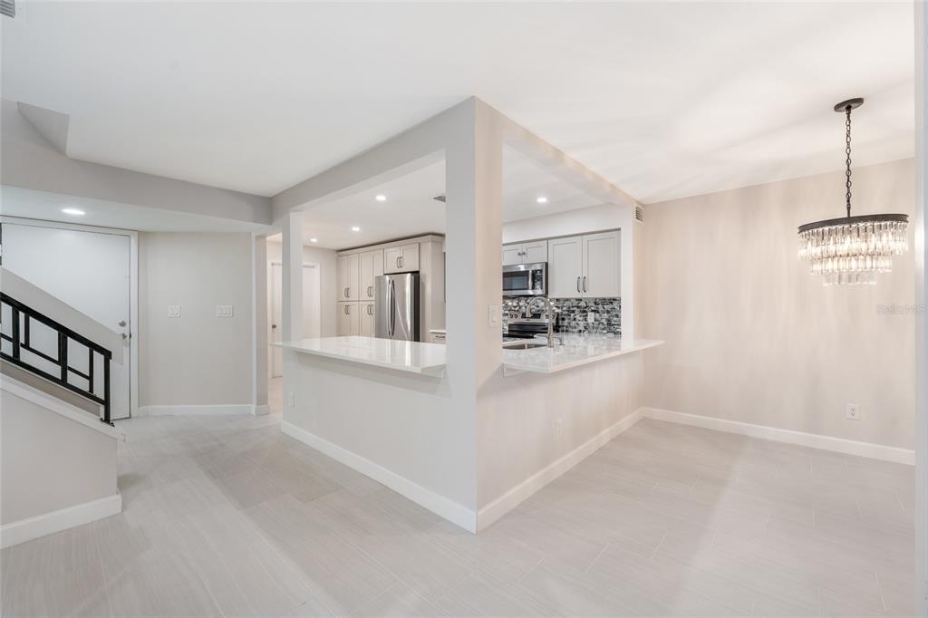A kitchen with white cabinets and quartz countertops opens to a dining area with tile — 8137 CITRUS CHASE DRIVE, ORLANDO, FL
