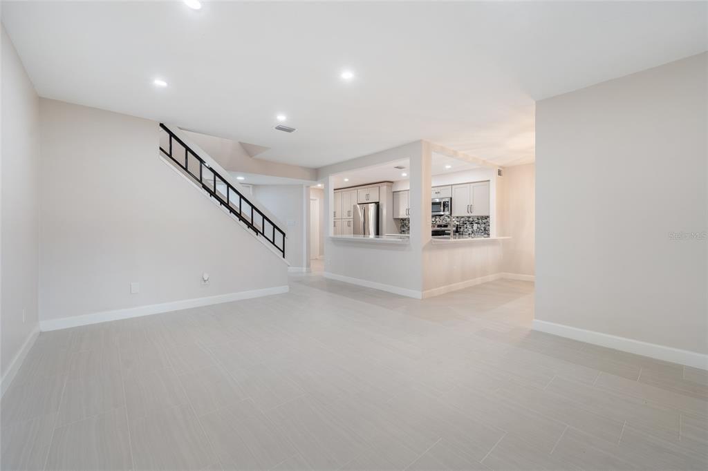A bright, open-concept living area features light tile flooring, a staircase, and a kitchen pass-through — 8137 CITRUS CHASE DRIVE, ORLANDO, FL