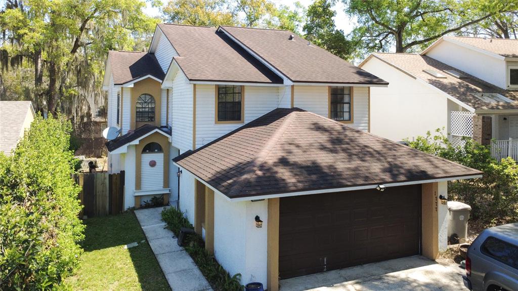 An elevated exterior view of a two-story house with white siding, tan trim, and a garage — 1777 SUMMIT CHASE AVENUE, APOPKA, FL