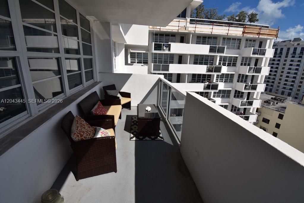 A balcony with outdoor furniture overlooks a neighboring multi-story apartment building — 100 Lincoln Rd # 1507, Miami Beach FL 33139, MIAMI BEACH, FL