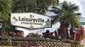 A sign for Leisureville, a 55+ private golf community, stands behind a brick garden wall — 2475 W Golf Boulevard # 243, Pompano Beach FL 33064, POMPANO BEACH, FL