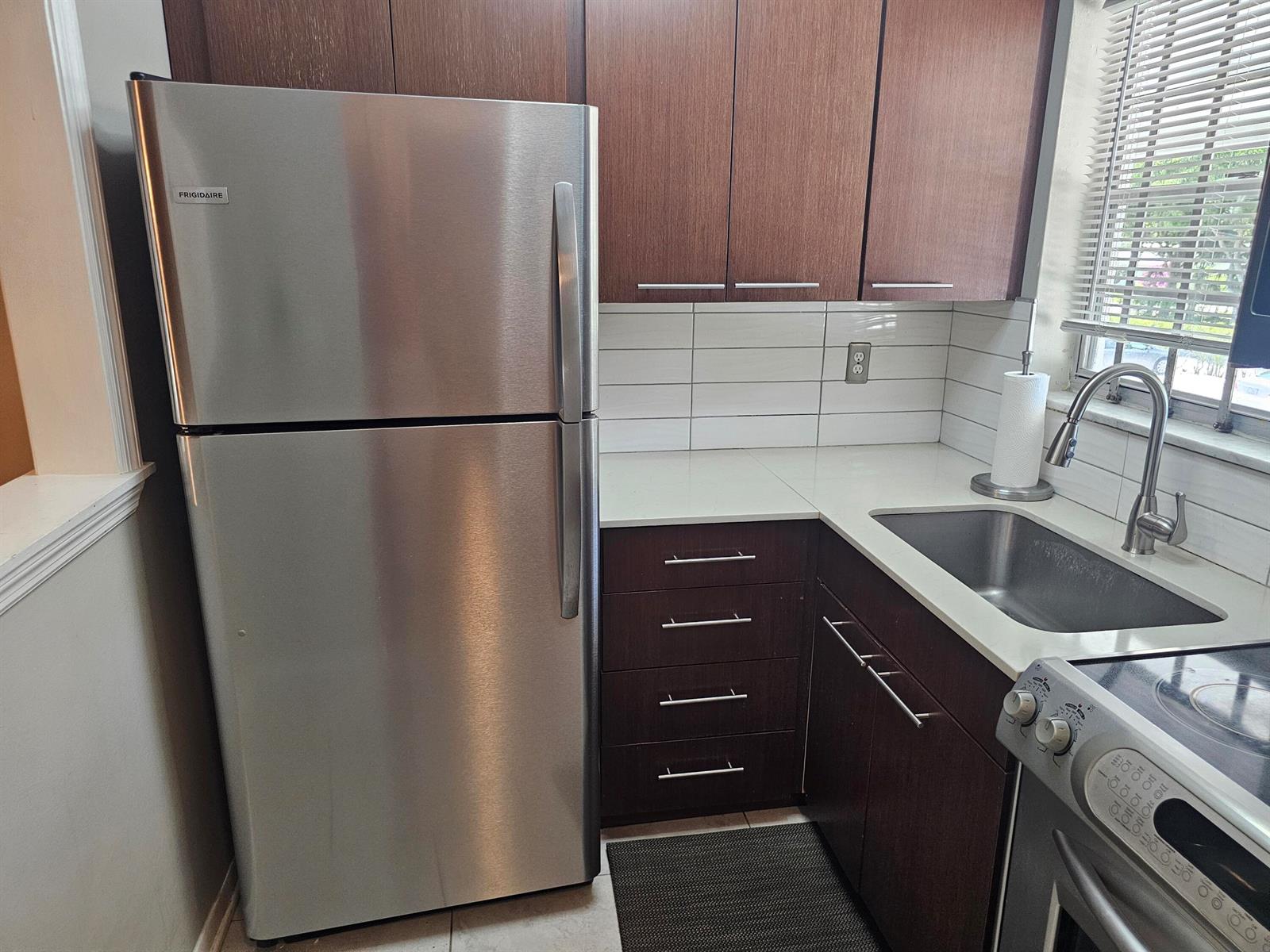 A kitchen features stainless steel appliances, dark wood cabinets, and white countertops — 2475 W Golf Boulevard # 243, Pompano Beach FL 33064, POMPANO BEACH, FL