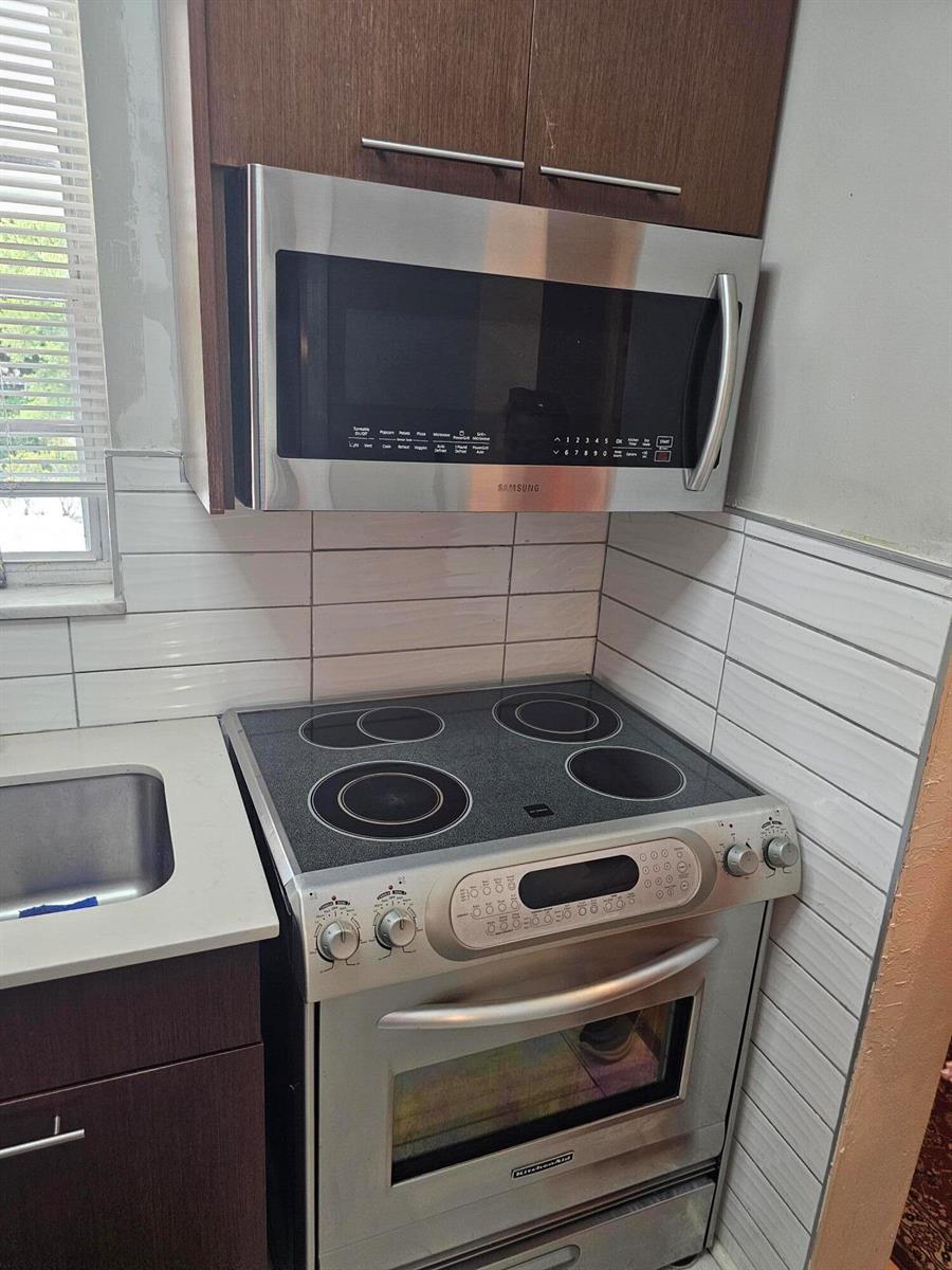 A kitchen features a stainless steel microwave above a glass-top electric range and sink — 2475 W Golf Boulevard # 243, Pompano Beach FL 33064, POMPANO BEACH, FL