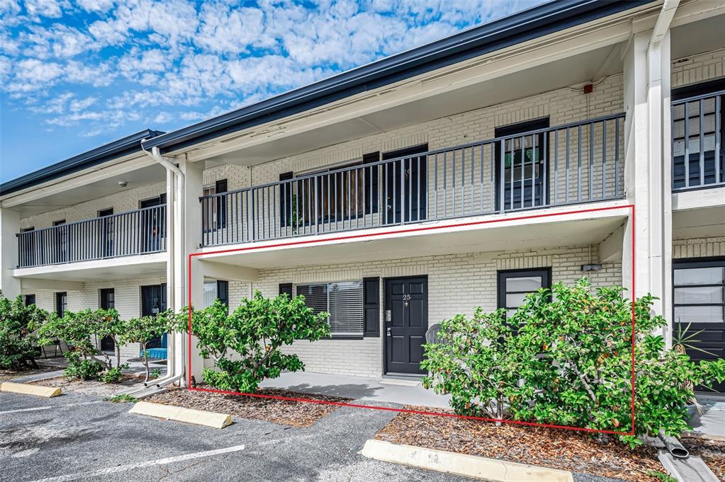 A two-story apartment building with white brick exterior, black trim, and a ground-floor unit highlighted — 2 N FERNWOOD AVENUE UNIT 25, CLEARWATER, FL