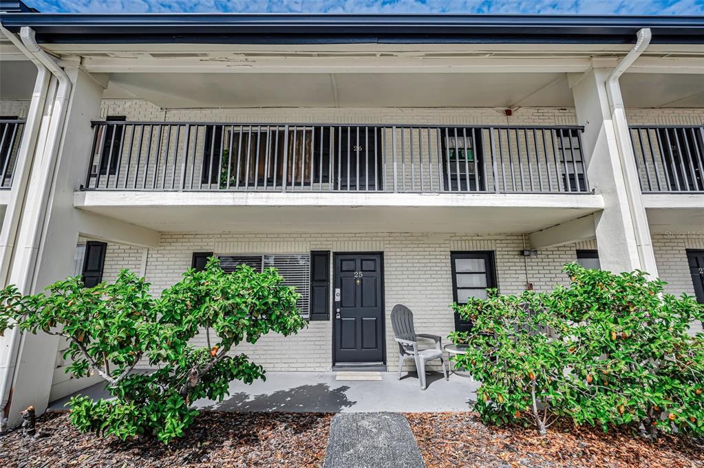 A two-story white brick townhouse exterior features a black front door and a balcony — 2 N FERNWOOD AVENUE UNIT 25, CLEARWATER, FL