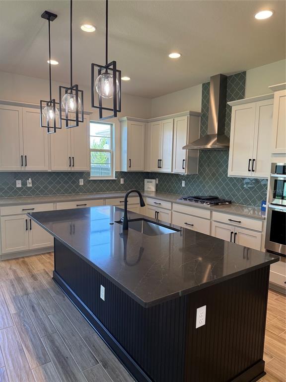 A kitchen features a dark island with a sink, white cabinetry, and green patterned backsplash — 5279 BUTTONSAGE DRIVE, ST CLOUD, FL