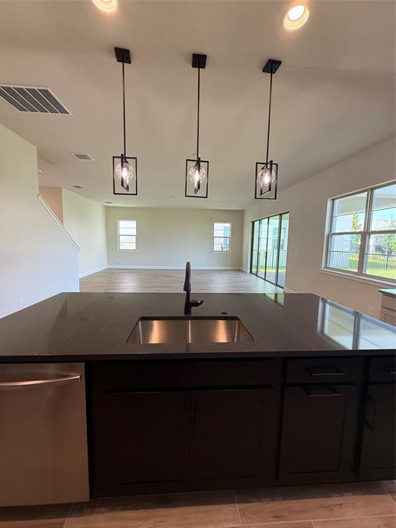 A kitchen island with a stainless steel sink and dark cabinetry sits before an open living area — 5279 BUTTONSAGE DRIVE, ST CLOUD, FL