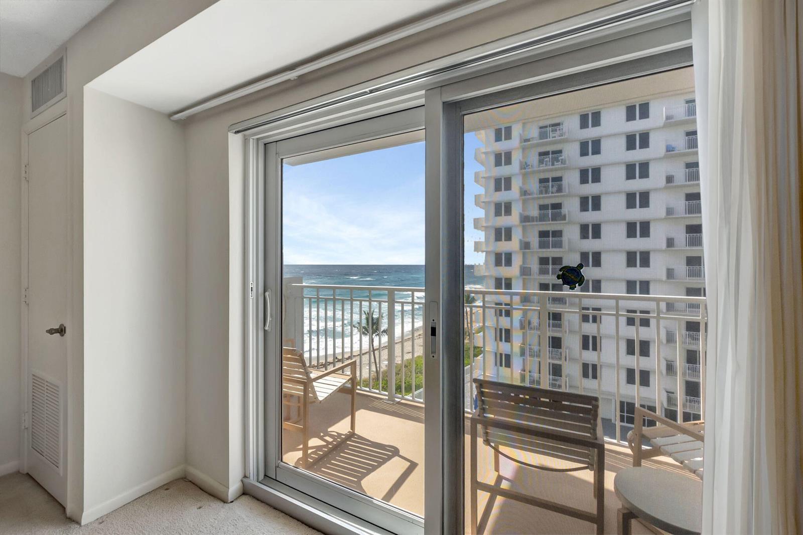 A view from an indoor room through sliding glass doors to a balcony overlooking the ocean — 3215 S Ocean Boulevard # 509, Highland Beach FL 33487, HIGHLAND BEACH, FL