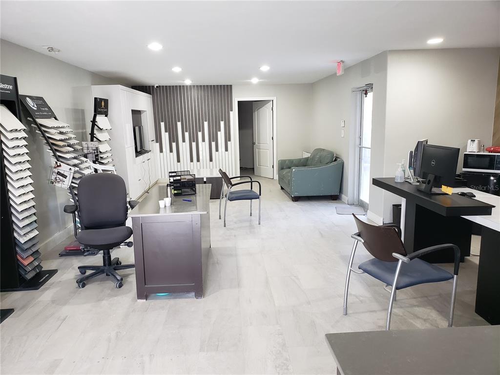 An office space features a desk, chairs, a sample display rack, and light-colored tile flooring — 5010 N GRADY AVENUE, TAMPA, FL