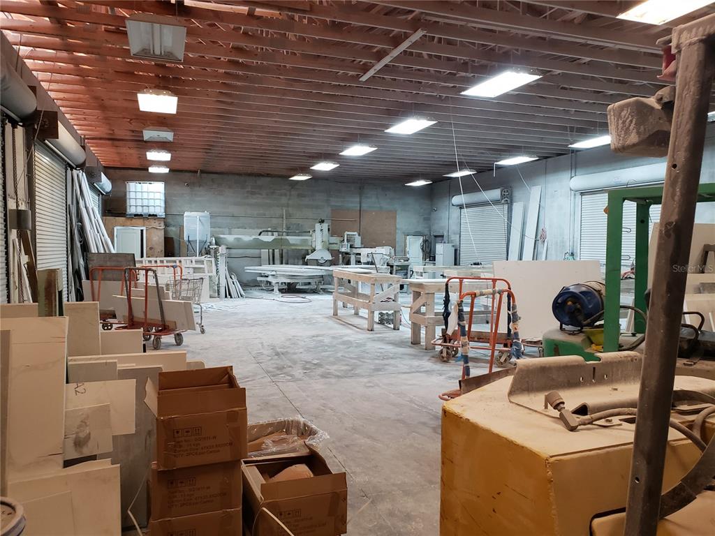 This industrial workshop features concrete block walls, exposed ceiling joists, and heavy stone-cutting machinery — 5010 N GRADY AVENUE, TAMPA, FL