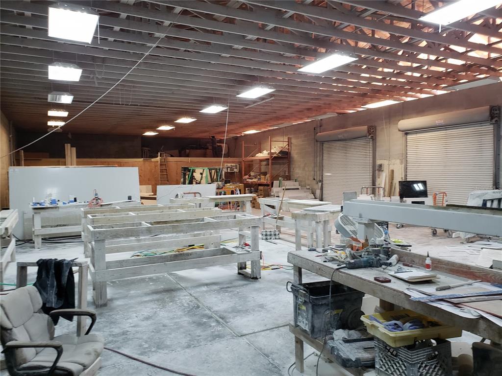 This industrial workshop features exposed ceiling joists, concrete floors, and multiple wooden workbenches — 5010 N GRADY AVENUE, TAMPA, FL