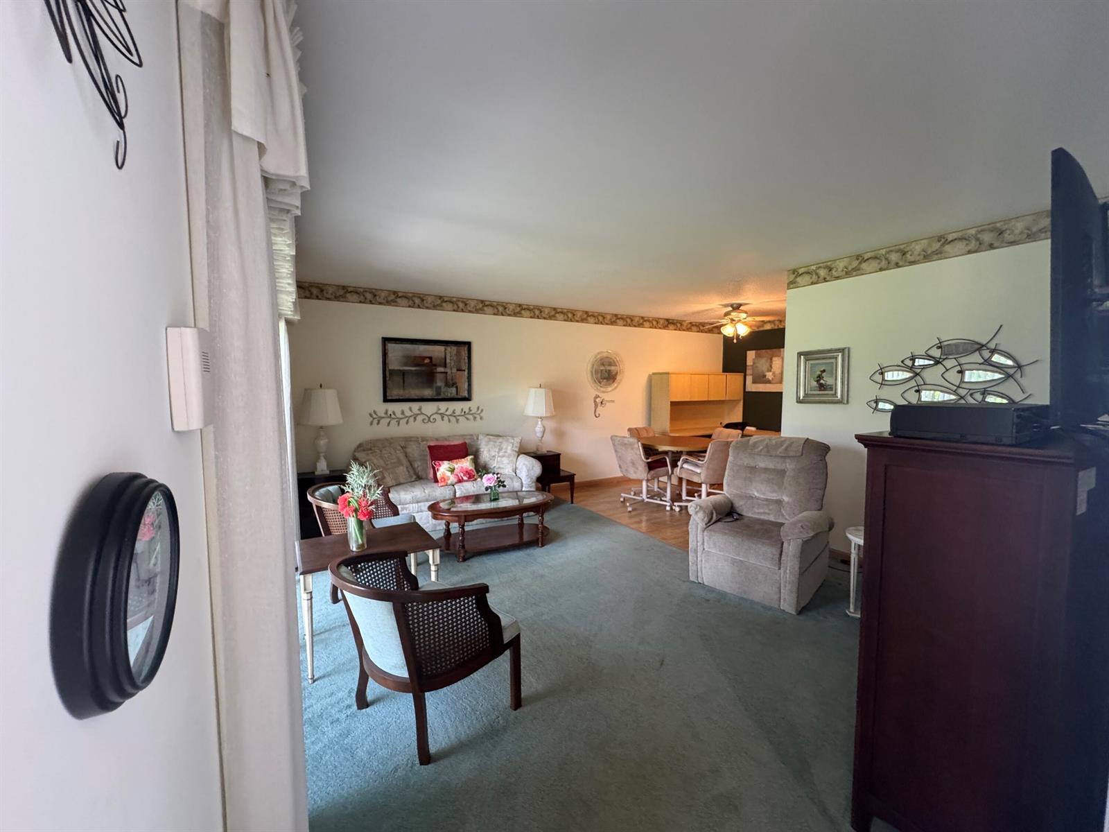 A living room features green carpeting, a beige sofa, a recliner, and a dining area — 115 S South Boulevard # 1c, Boynton Beach FL 33435, BOYNTON BEACH, FL