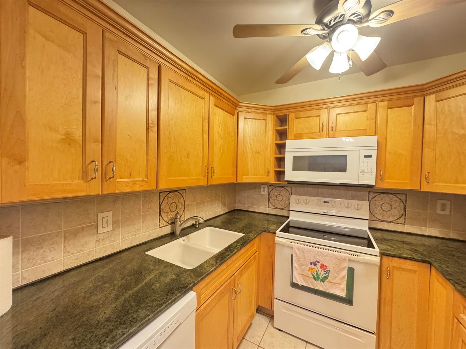 A kitchen features light wood cabinets, dark green countertops, a white stove, and a ceiling fan — 115 S South Boulevard # 1c, Boynton Beach FL 33435, BOYNTON BEACH, FL