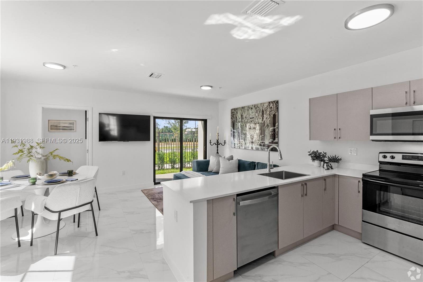 This open-concept kitchen and living area features white tile floors, light cabinetry, and stainless appliances — 2320 E 4th Ave # 102, Hialeah FL 33013, HIALEAH, FL