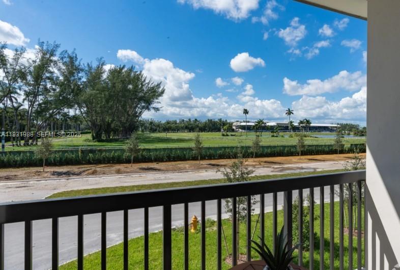 A balcony view overlooks a road, a grassy field, and a distant building under clouds — 2320 E 4th Ave # 102, Hialeah FL 33013, HIALEAH, FL