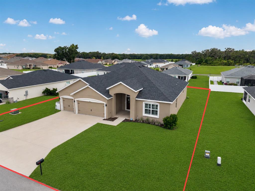 An aerial view shows a tan, single-story suburban house with a dark roof and a large lawn — 9074 SE 48TH COURT ROAD, OCALA, FL