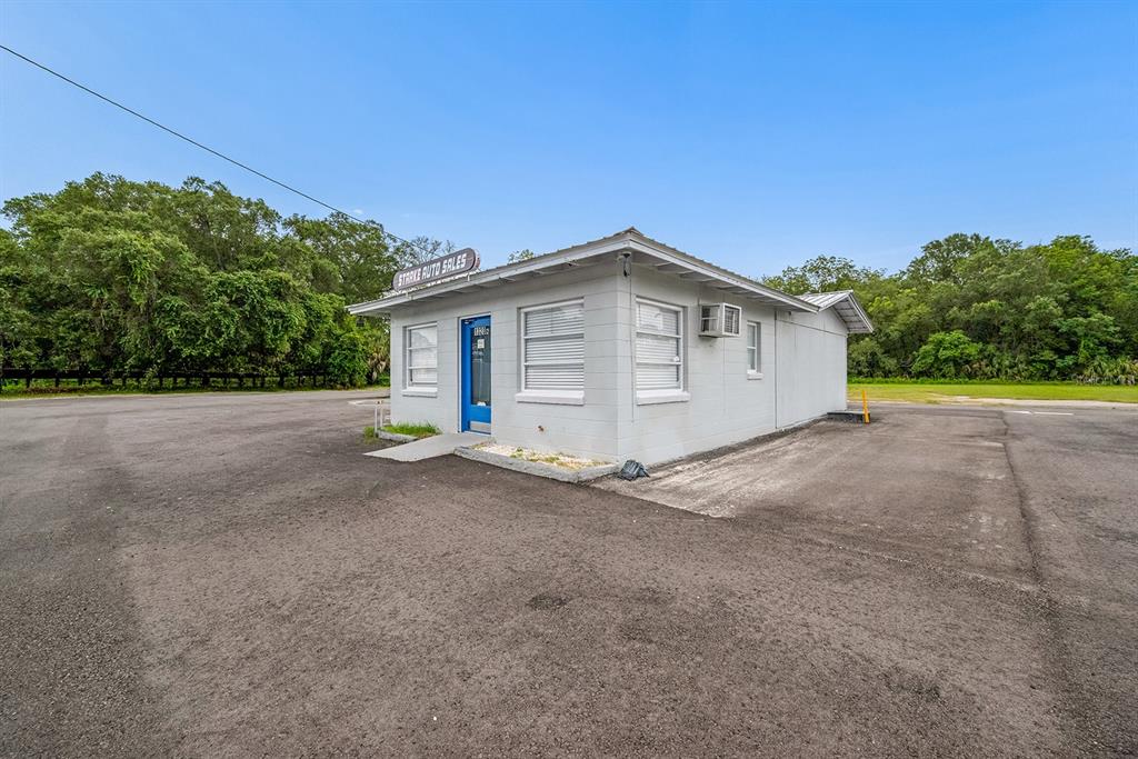 A small, single-story gray commercial building with a blue door sits on a paved lot — 1320 N TEMPLE AVENUE, STARKE, FL