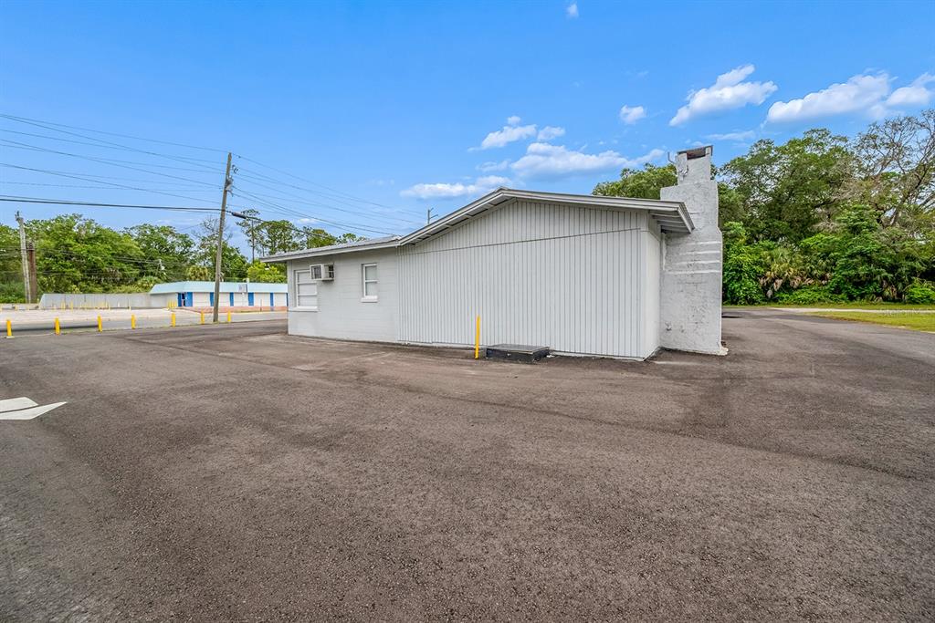 A single-story gray building with a chimney stands in a large, paved parking lot — 1320 N TEMPLE AVENUE, STARKE, FL