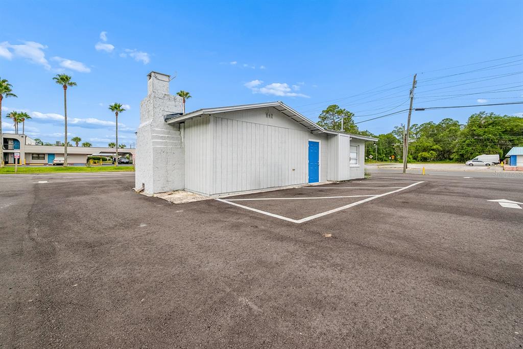 A single-story building with a white chimney and a blue door in a parking lot — 1320 N TEMPLE AVENUE, STARKE, FL