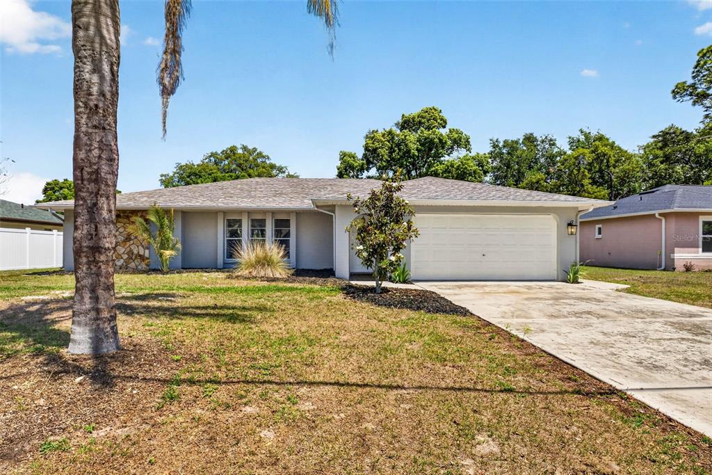 A single-story house with a gray exterior, a two-car garage, and a palm tree — 9043 MCCORMICK STREET, SPRING HILL, FL