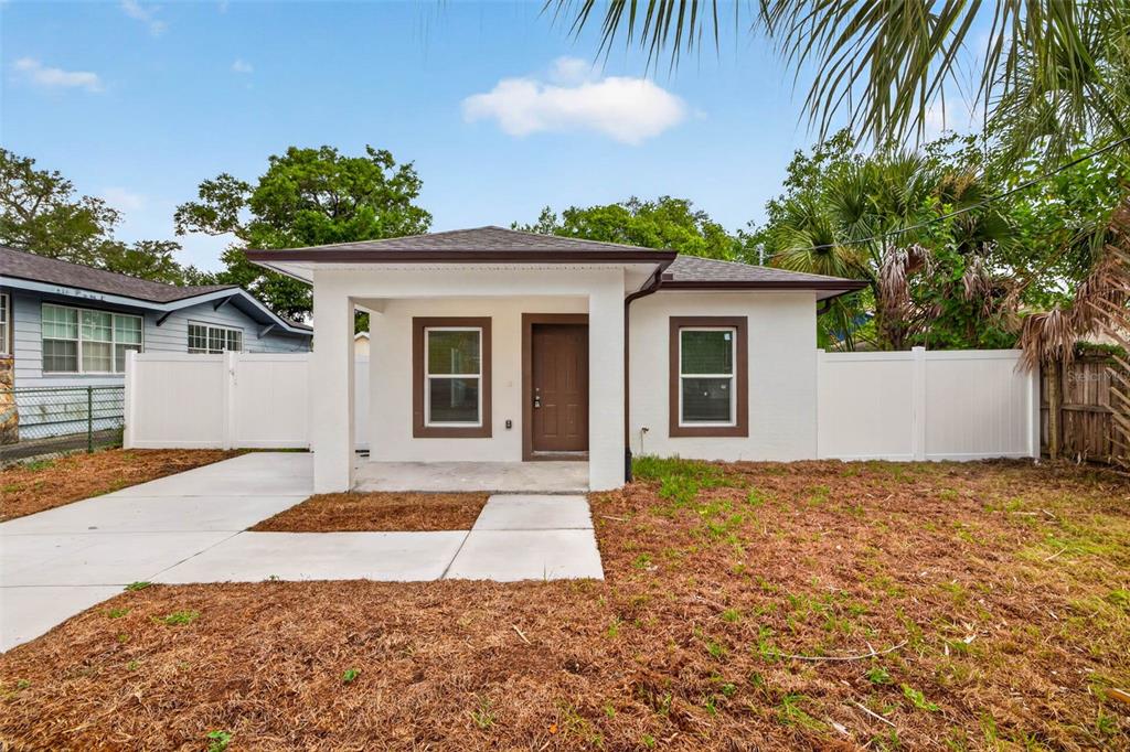 A white, single-story house features a brown front door, dark-trimmed windows, and a concrete walkway — 3420 N 10TH STREET, TAMPA, FL