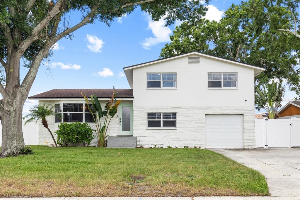 A two-story white house with a brick facade, a front lawn, and a garage — 10716 DONBRESE AVENUE, TAMPA, FL