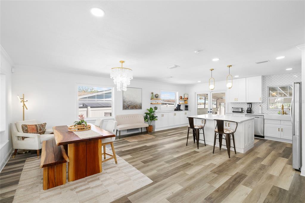 An open-concept kitchen and dining area features white cabinetry, a wood table, and wood-look flooring — 10716 DONBRESE AVENUE, TAMPA, FL