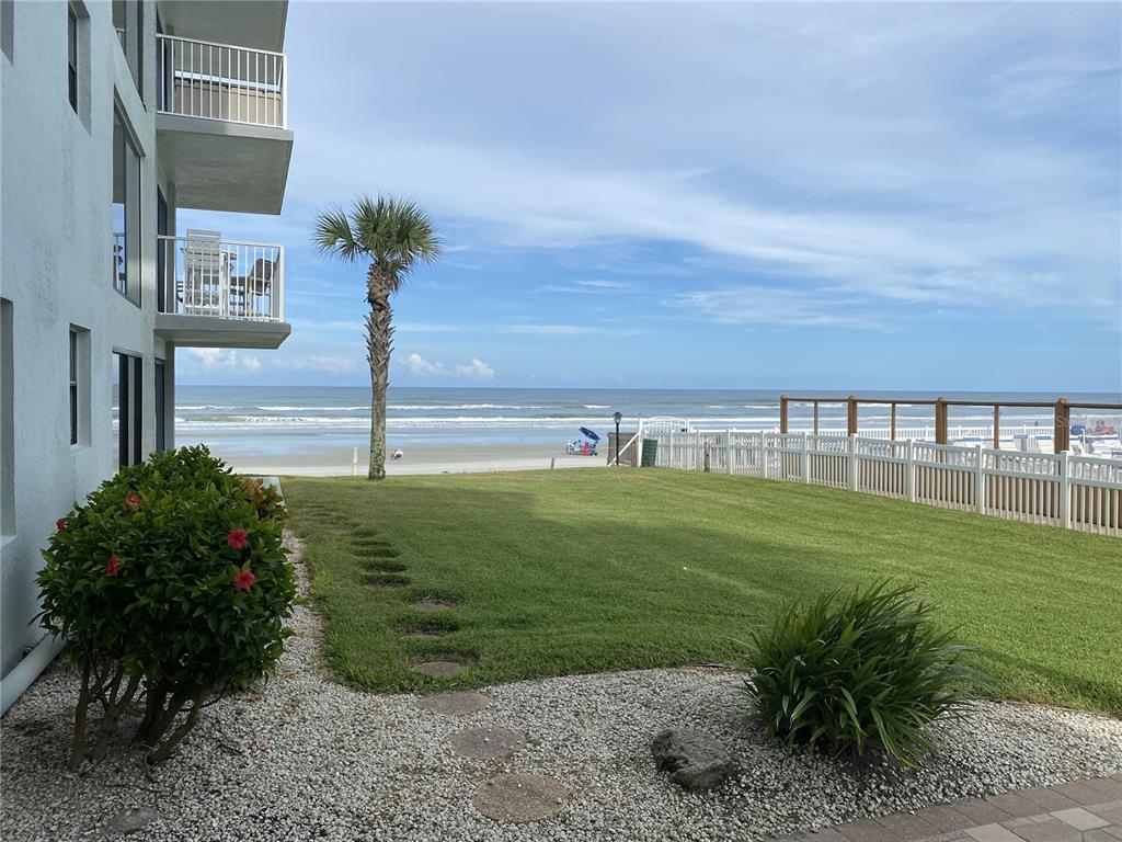 A grassy lawn leads to a white fence overlooking the beach and ocean — 1571 S ATLANTIC AVENUE UNIT 108, NEW SMYRNA BEACH, FL