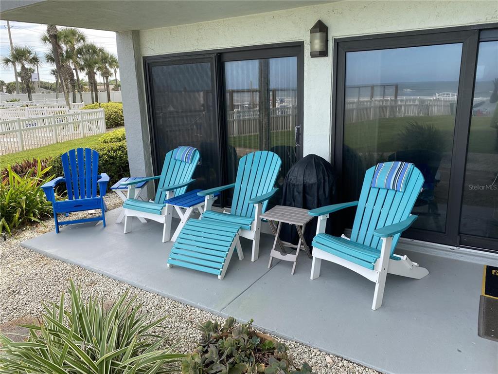 A concrete patio features four Adirondack chairs, a small side table, and a covered grill — 1571 S ATLANTIC AVENUE UNIT 108, NEW SMYRNA BEACH, FL