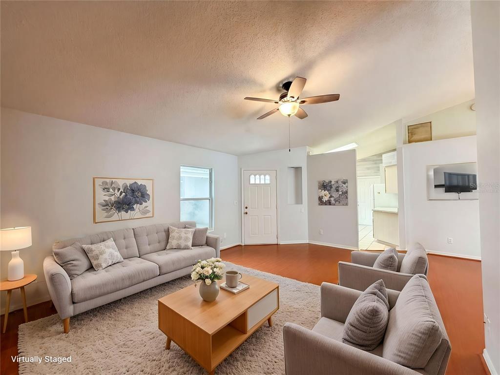 A living room features a grey sofa, two armchairs, a coffee table, and wood flooring — 5507 LAVER STREET, LEESBURG, FL