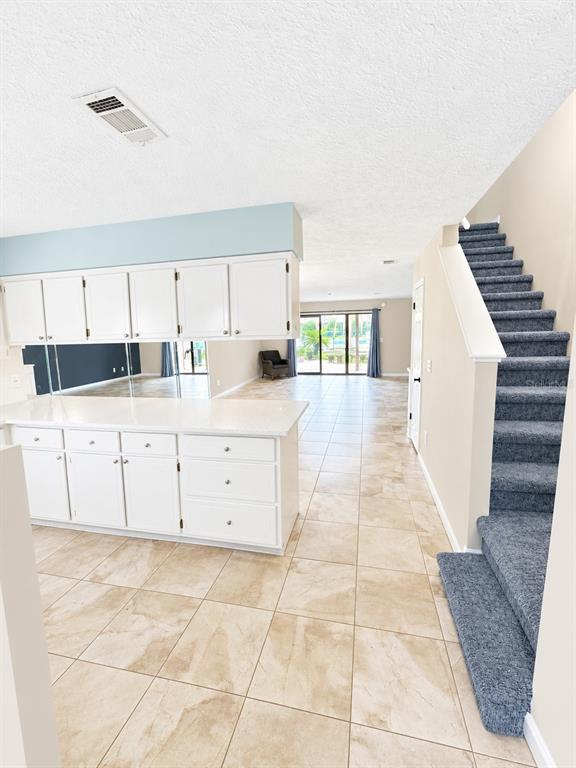 A kitchen with white cabinets and a quartz countertop overlooks a living area with stairs — 143 GRANDE ISLAND BLVD BOULEVARD, PANAMA CITY BEACH, FL