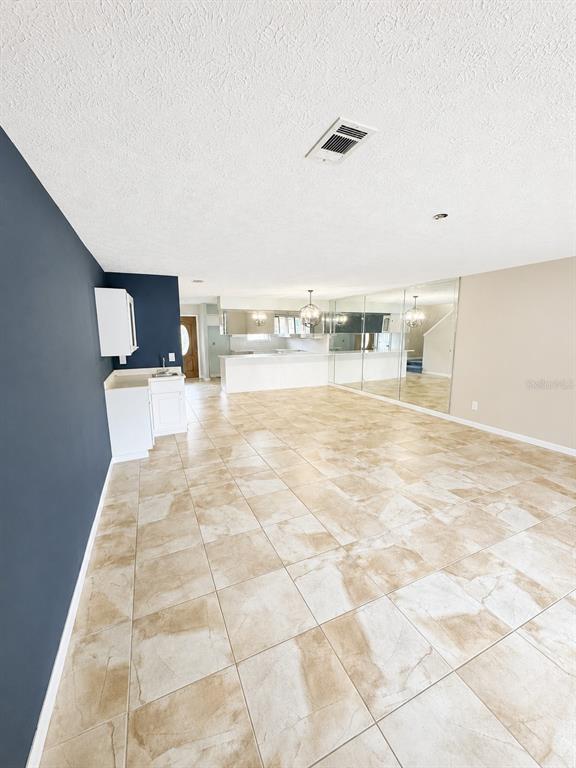 A room with beige tile flooring, a dark blue accent wall, and a large chandelier — 143 GRANDE ISLAND BLVD BOULEVARD, PANAMA CITY BEACH, FL