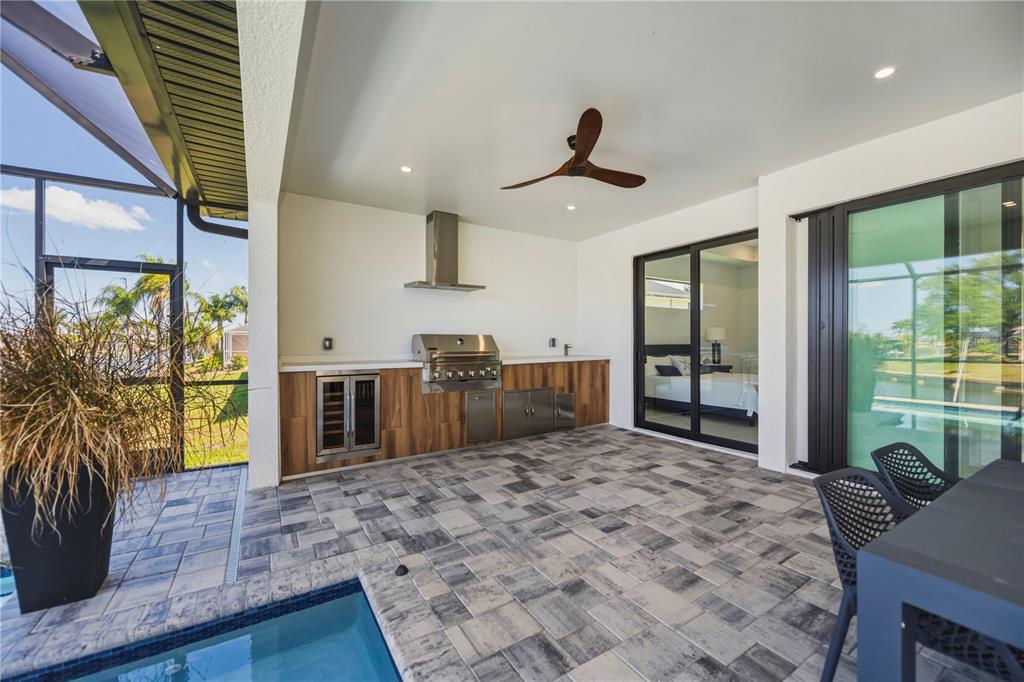 A covered outdoor patio features a built-in grill, wood-look cabinets, and a small pool — 9493 ST PAUL DRIVE, PORT CHARLOTTE, FL