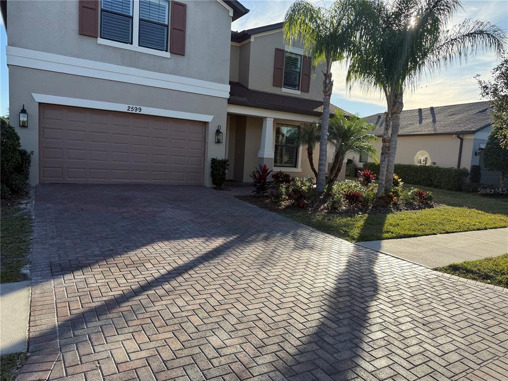 A two-story house features a brick paver driveway, a garage, and a palm tree — 2599 MARTON OAK BOULEVARD, NORTH PORT, FL
