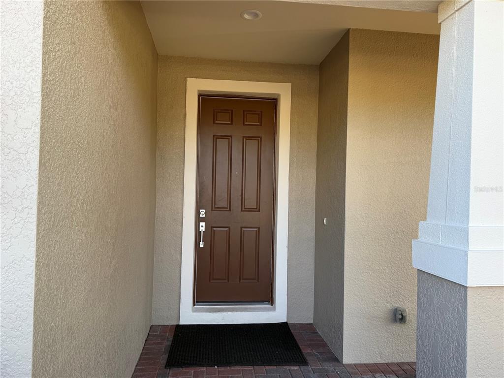 A brown front door with six panels is set within a covered entryway — 2599 MARTON OAK BOULEVARD, NORTH PORT, FL