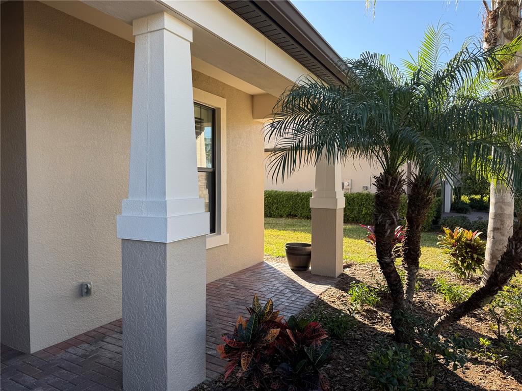 A covered porch features brick pavers, white tapered columns, and a view of landscaping — 2599 MARTON OAK BOULEVARD, NORTH PORT, FL