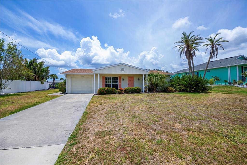 A single-story house with a beige exterior, a garage, and a front lawn — 18451 GOODMAN CIRCLE, PORT CHARLOTTE, FL