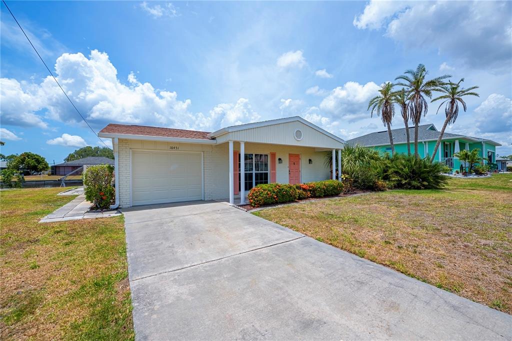 A single-story house with a garage, light-colored siding, and palm trees in the front yard — 18451 GOODMAN CIRCLE, PORT CHARLOTTE, FL
