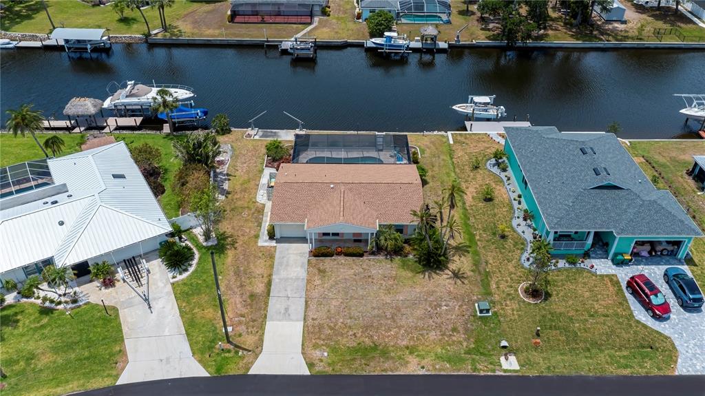 An aerial view shows three waterfront houses with boat docks along a canal — 18451 GOODMAN CIRCLE, PORT CHARLOTTE, FL