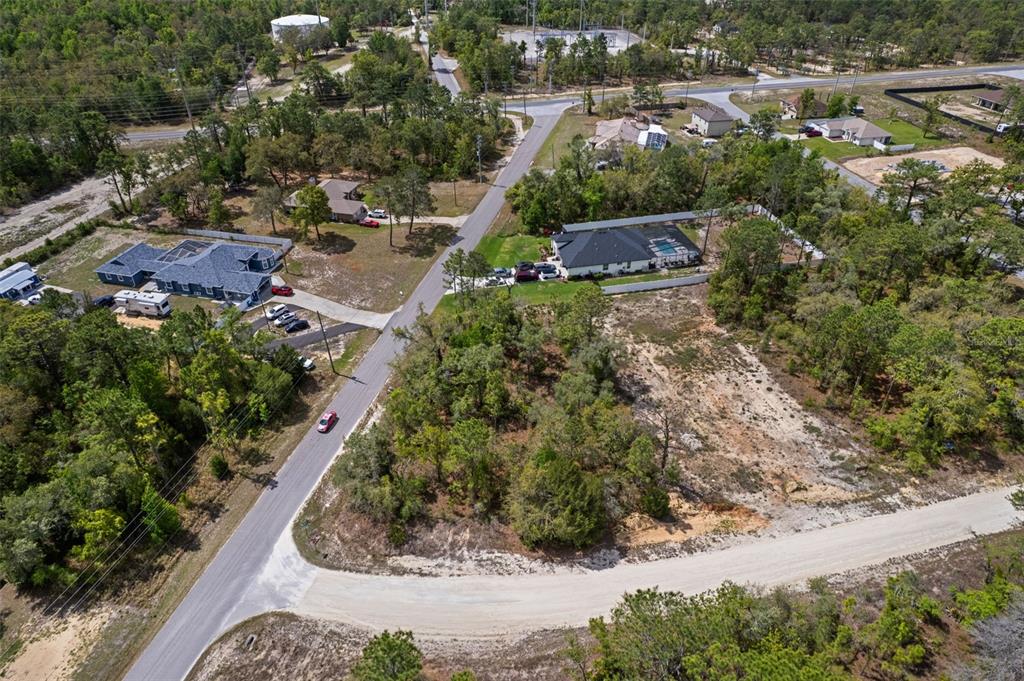An aerial view shows a residential neighborhood with houses, wooded lots, and paved roads — 12140 MISSISSIPPI KITE AVENUE, BROOKSVILLE, FL