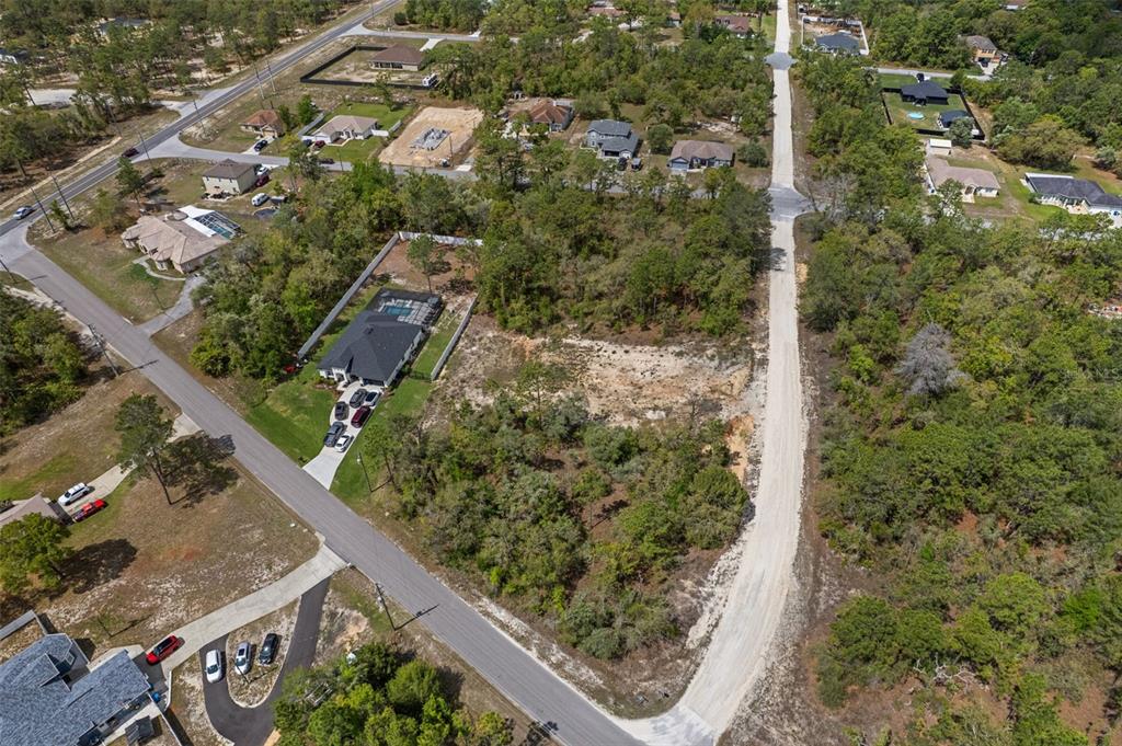 An aerial view shows a vacant residential lot surrounded by trees and neighboring houses — 12140 MISSISSIPPI KITE AVENUE, BROOKSVILLE, FL
