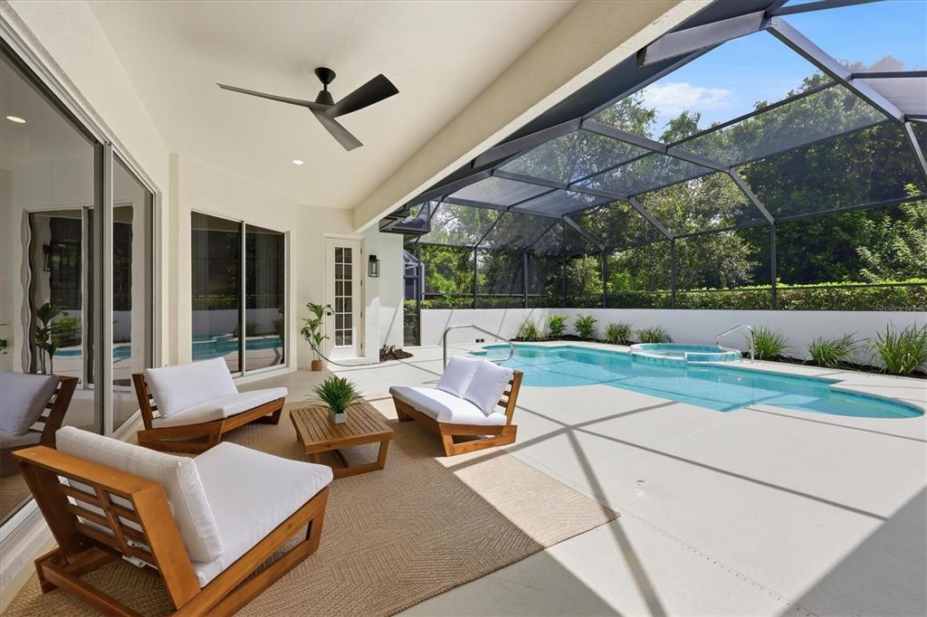 A covered patio features outdoor seating, a ceiling fan, and a screened-in pool and spa — 7825 WILTON CRESCENT CIRCLE, BRADENTON, FL