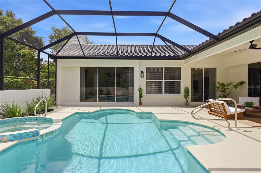 A screened-in patio features a swimming pool, a spa, and sliding glass doors to the home — 7825 WILTON CRESCENT CIRCLE, BRADENTON, FL