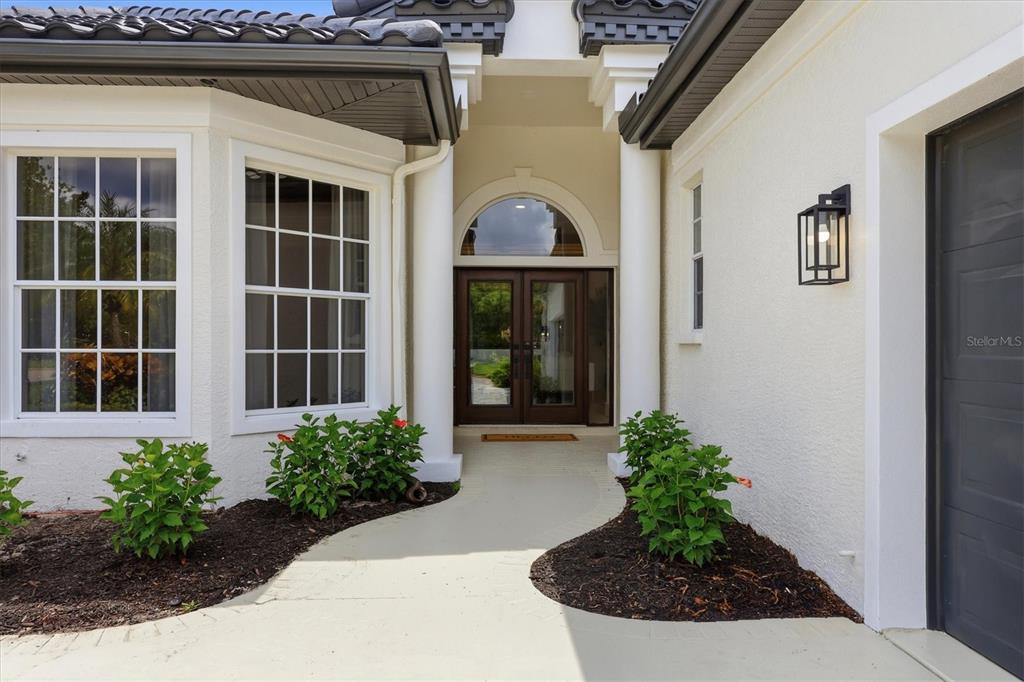The exterior view shows a front entrance with double doors, white columns, and landscaping — 7825 WILTON CRESCENT CIRCLE, BRADENTON, FL