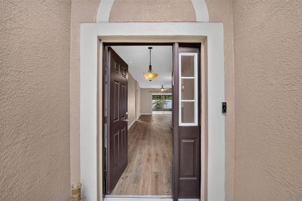An open front door reveals a view into a home with wood-look flooring — 5605 HAWKLAKE ROAD, LITHIA, FL