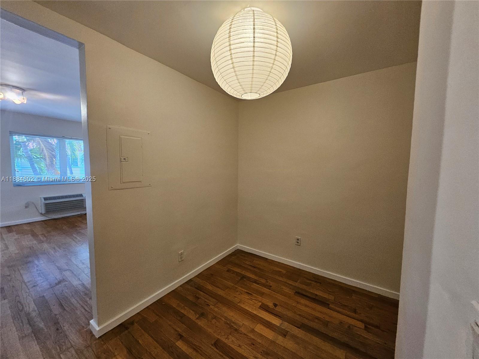 This small room features hardwood floors, a paper globe pendant light, and a wall panel — 745 13th St # 16, Miami Beach FL 33139, MIAMI BEACH, FL