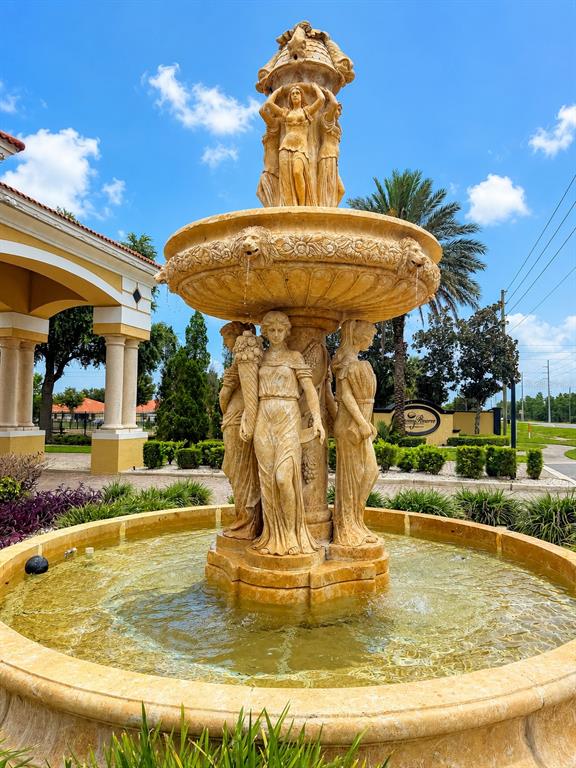 A large, tiered stone fountain with sculpted female figures stands in front of a building — 1644 CUMIN DRIVE, POINCIANA, FL