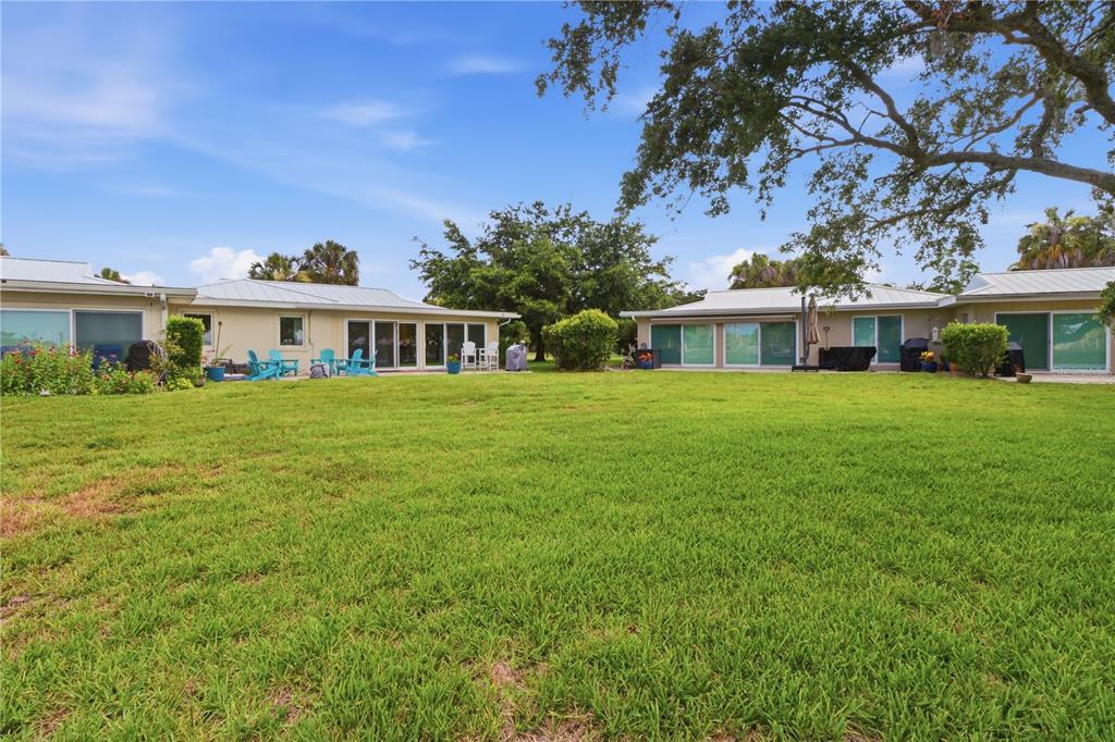 A wide grassy backyard sits in front of two single-story buildings with sliding glass doors — 11628 W BAYSHORE DRIVE UNIT 8, CRYSTAL RIVER, FL