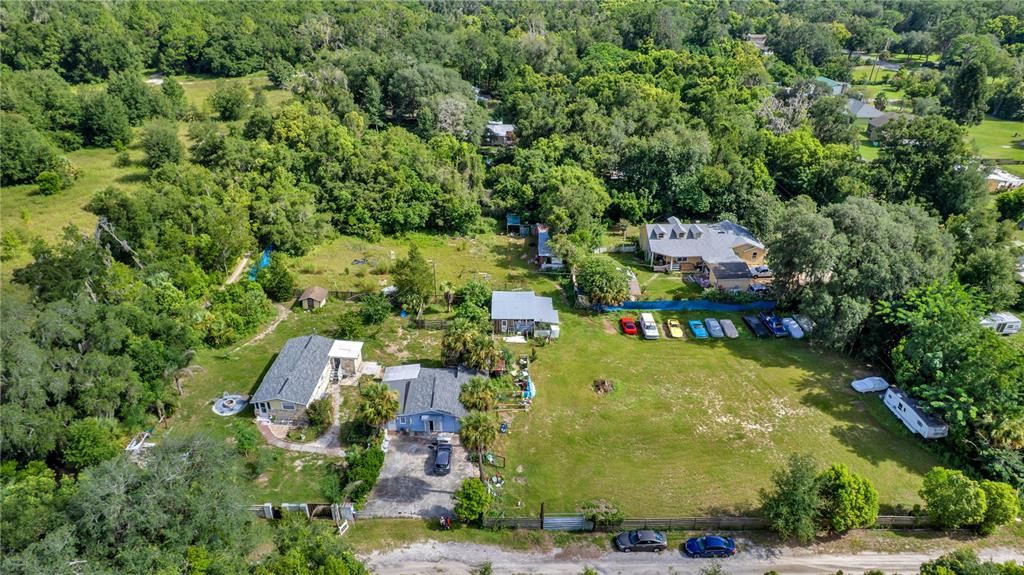 An aerial view shows a large, grassy lot containing several houses and parked vehicles — 405 W SIMON AVENUE, APOPKA, FL